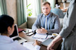 © Seventyfour - Young businessman sitting at the table and listening to his colleague at business meeting in a cafe