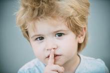 Boy With Finger On Lips Making A Silent Gesture. Please Be Quiet. Smart Cute Young Boy With His Finger Over His Lips Being Quiet. Little Boy Showing Silence Symbol Gesture. Secret Young Kid Guy