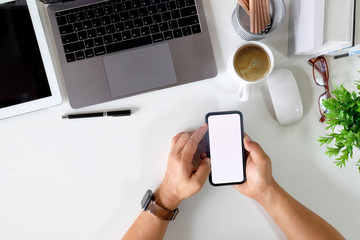 Man holding blank screen smart phone on desk in office.