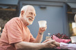© Yakobchuk Olena - Side view of delighted senior male drinking tea with spouse outside. He is holding tenderly her hand and looking at her with sincere smile