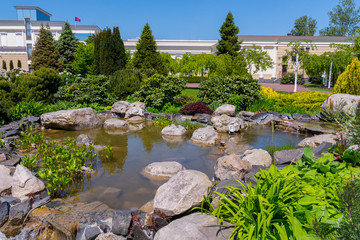 planting ornamental shrubs and trees near a stony pool with a cascade fountain in the botanical garden