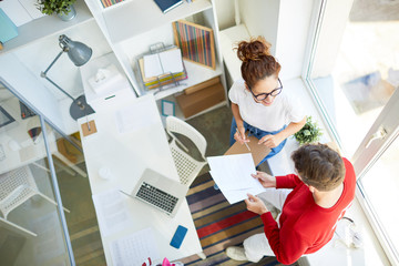 Canvas Print - Young creative office workers discussing papers and new ideas for their project