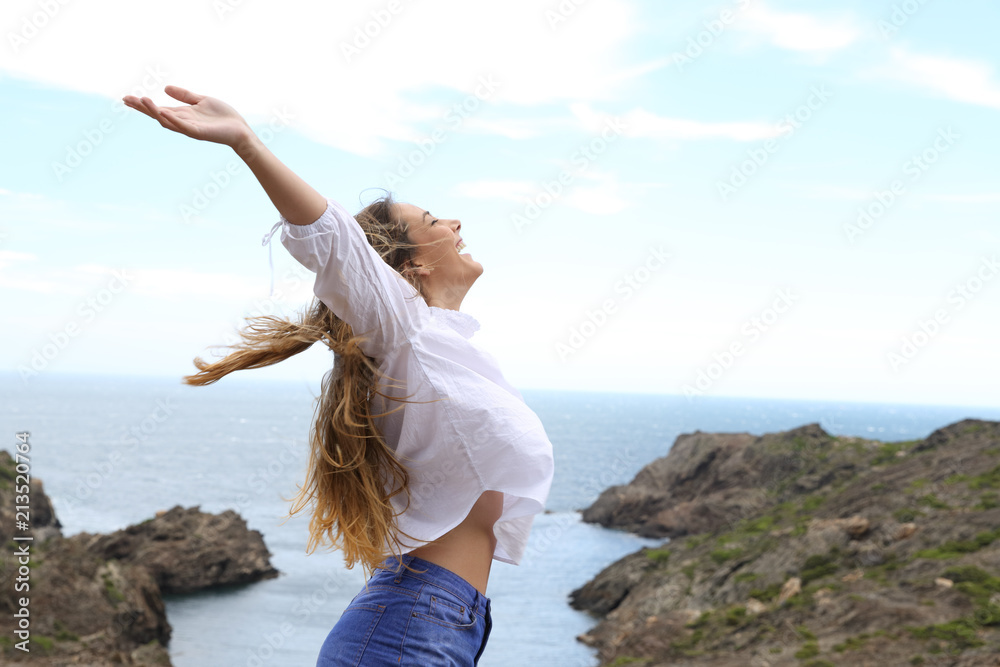Side view of a joyful girl raising arms to the wind - obrazy, fototapety, plakaty 