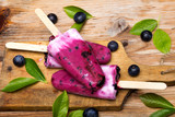 Fototapeta  - Smaczne domowe jagodowe, borówkowe lody na patyku na drewnianym tle. Organiczne lody owocowe. 