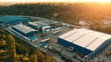 Fototapeta  - Aerial view of warehouse storages or industrial factory or logistics center from above. Aerial view of industrial buildings at sunset