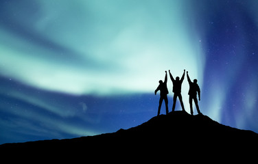 Wall Mural - silhouette of a team at the northen light background. sport and active life concept and idea of team