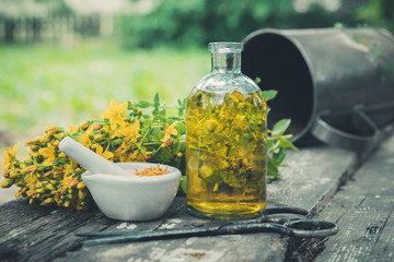 Wall Mural - Hypericum - St Johns wort flowers, oil or infusion transparent bottle, mortar on wooden table.