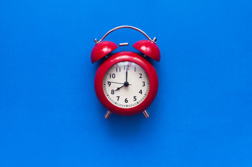 Red alarm clock isolated on blue background with copy space.