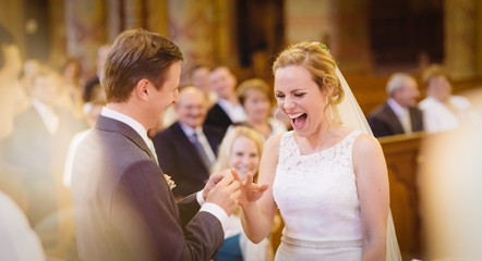 bride smiling happiness at own wedding, groom putting ring, crowd happy