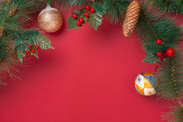 Poster - Christmas decoration and fir branches wreath with cherry and pine cone on red table background. winter holiday festive celebration concept.copy space for greeting card.