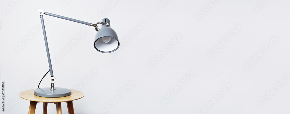 A gray table lamp in the interior against a white wall. The concept of business or education with a place for your text. Detail of interior, minimalism background. - obrazy, fototapety, plakaty 