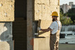 © LIGHTFIELD STUDIOS - Side view of builder in protective helmet and googles doing insulation of wall at construction site