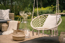 Pillow On Hanging Chair And Basket On Carpet In The Garden During Spring