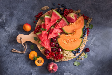 Fresh sliced watermelon and cantaloupe, summer fruits and berries on round cutting board, ready to eat, vegan raw eating, diet vitamins concept