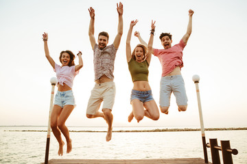 Sticker - Friends loving couples jumping outdoors on the beach.