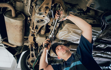 Wall Mural - Car mechanic repair car suspension of lifted automobile at repair service station