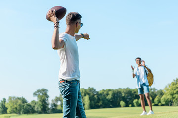 Wall Mural - multiethnic teenage boys playing with rugby ball in park