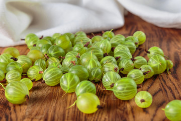 gooseberry berries lie on the oak surface of the table on the background of a white towel