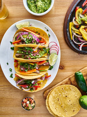 Wall Mural - tasty mexican tacos with beef fajita filling served with salsa and guacamole in flat lay composition