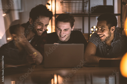 Cuadros en Lienzo Happy friends watching movie on laptop during meeting on Saturday night at home