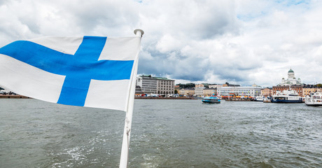 Wall Mural - A Finnish flag on a boat, develops in the wind with a view of the sea. Travel to Finland, Scandinavian Europe