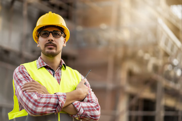 Handsome engineer supervising construction work on site.