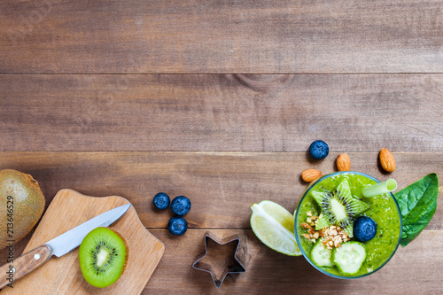 Fotografía Wooden background with glass of green healthy smoothie