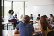 © Monkey Business - Female High School Tutor Sitting At Table With Pupils Teaching Maths Class