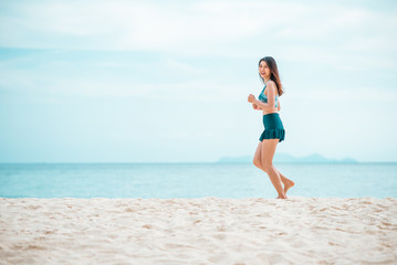 Happy Asian woman jogging on the beach in the morning