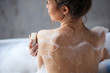 close up cropped back view photo of slim beautiful woman with perfect body sitting in the bathtub and using the soap