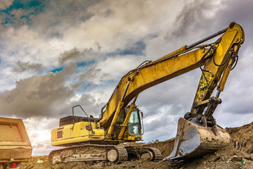 Wall Mural - Excavator loading earth to perform works of settlement of a road