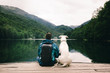 © minastefanovic - Man sitting with a dog on dock at the lake