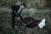 Male Murderer With A Shovel Is Digging A Grave