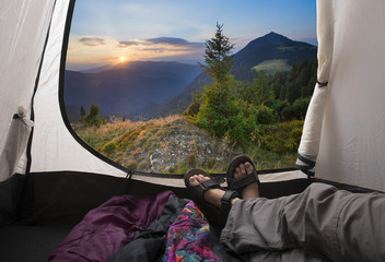 Two people lying in tent with a view of mountains.