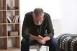 © New Africa - Depressed senior man sitting on stool indoors