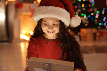 Wall Mural - Cute little child in Santa hat with Christmas gift box at home