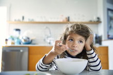 Girl Looking Away While Eating Food On Table At Home