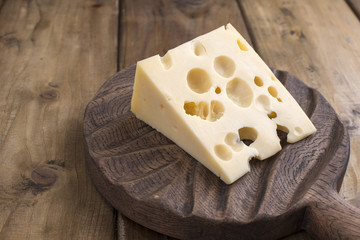 dutch cheese with holes on a wooden old board. vintage photo. dairy. free space for text. copy space