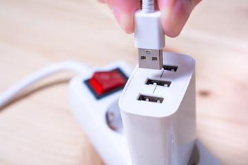 Connecting A White USB Cable To A White USB Charger Which Is Plugged Into A Power Strip