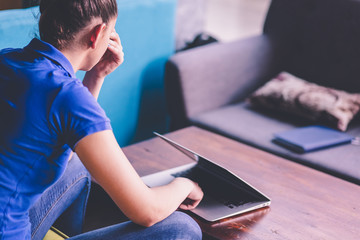 Wall Mural - Portrait of young bored attractive female student looking at laptop.