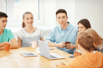 Poster - Group of cool teenagers with modern devices resting in cafe