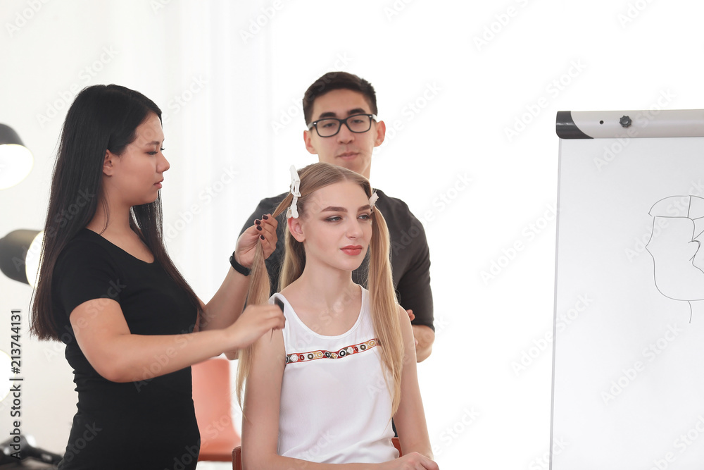 Professional hairdresser and trainee working with client in salon. Apprenticeship concept