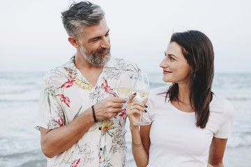 Wall Mural - Couple enjoying a glass of wine by the beach