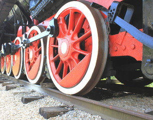 Red large iron wheels of an old vintage locomotive on iron rails close-up