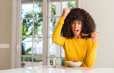 Poster - African american woman eating pasta salad annoyed and frustrated shouting with anger, crazy and yelling with raised hand, anger concept