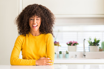 Sticker - African american woman wearing yellow sweater at kitchen winking looking at the camera with sexy expression, cheerful and happy face.