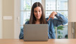 © Krakenimages.com - Young woman using laptop at home with surprise face pointing finger to himself