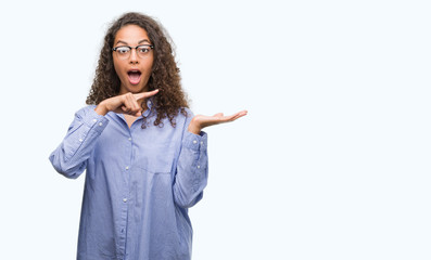 Beautiful young hispanic woman wearing glasses very happy pointing with hand and finger