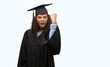 © Krakenimages.com - Young hispanic woman wearing graduation uniform annoyed and frustrated shouting with anger, crazy and yelling with raised hand, anger concept