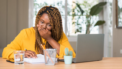 Canvas Print - African american woman studying with laptop cover mouth with hand shocked with shame for mistake, expression of fear, scared in silence, secret concept